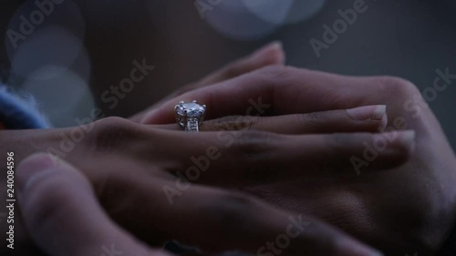 Male hand putting a ring on his partner's finger as he proposes, in slow motion  photo