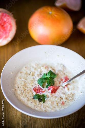 sweet oatmeal with slices of red grapefruit in a ceramic bowl