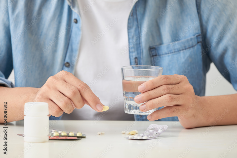 Man taking his pills on couch in the living room Man taking his pills on couch in the living room