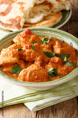 Indian Karhai chicken in a spicy sauce close-up served with naan bread. vertical © FomaA