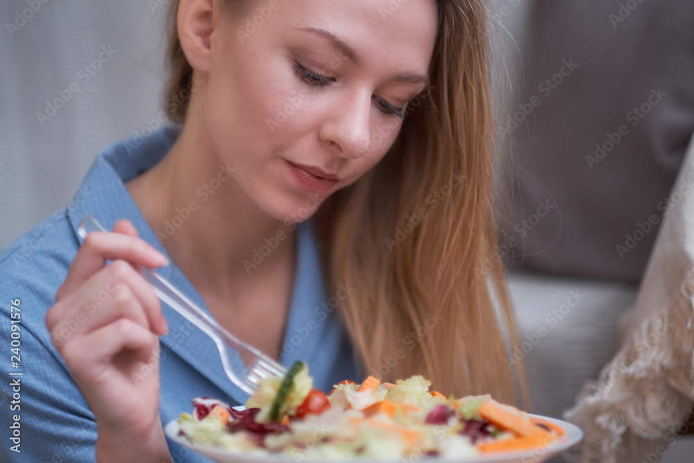 young woman is eating salad at home, diet concept. disgruntled person, depression from having to diet, lack of fat in the diet. young woman is eating salad at home, diet concept. disgruntled person, depression from having to diet, lack of fat in the diet.