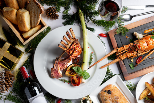 Luxury dinner menu grilled lamb, pasta lobster during Christmas and New year. Decrated with festive elements, wine, bred, red burry. Beautiful classic background with space. photo