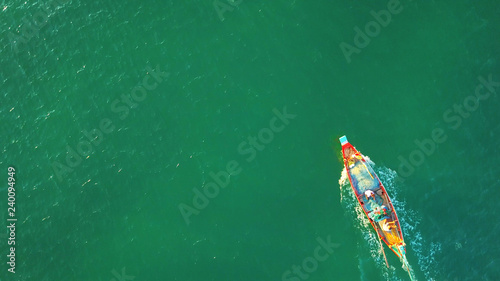 Traditional Thailand long-tail boat, floats and moves forward in the middle of the sea. Wooden motor boat floating in the clear water