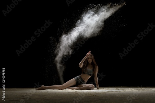 Girl in lingerie sitting in the dust in the dark