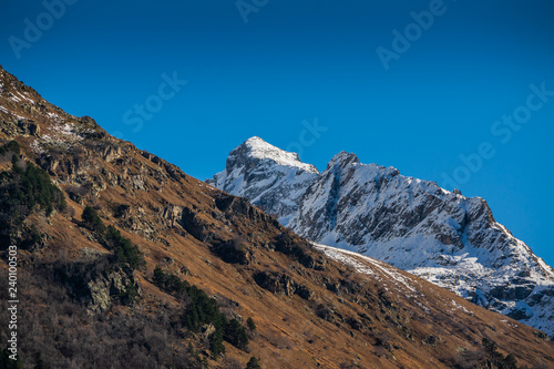landscape with snow capped mountain range and autumn forest, Caucasus mountains near Dombay, Russia