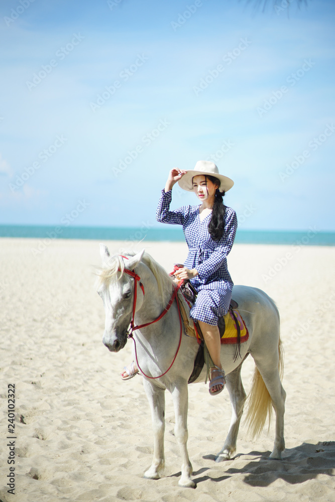 Beautiful woman riding a white horse at the beach