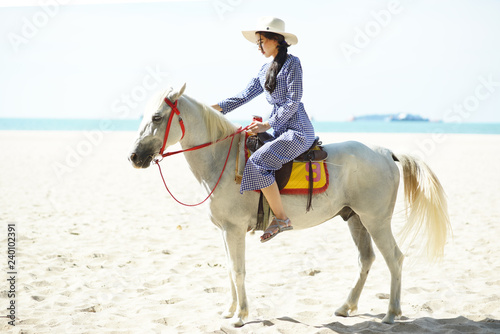 Beautiful woman riding a white horse at the beach
