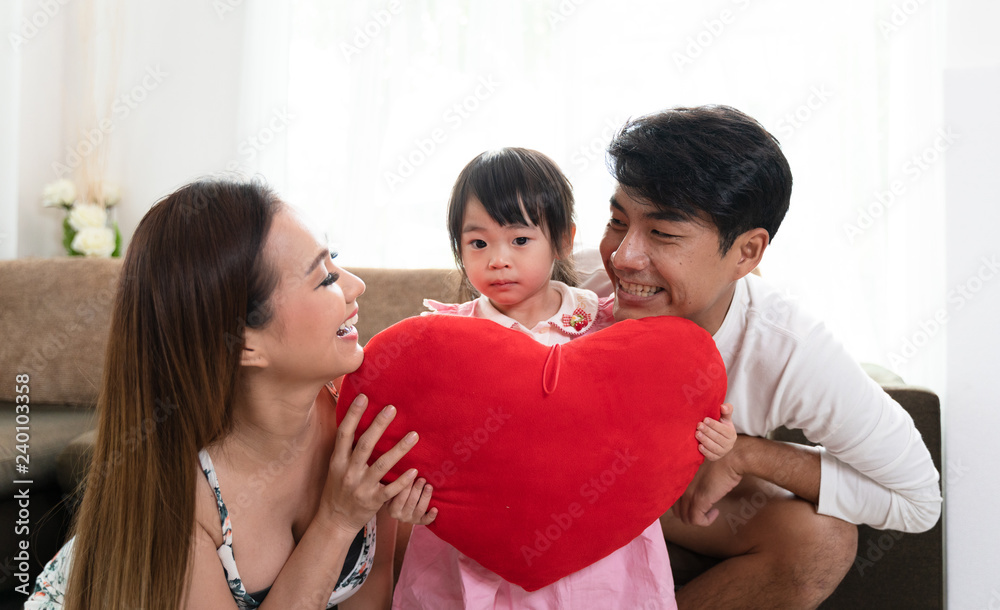 mother father and daughter holding heart pillow