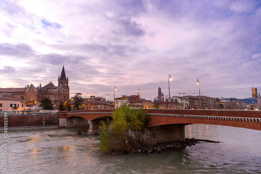 Evening view of Verona. Autumn in Verona, Italy. Scenery with Adige River and Ponte di Pietra.  Famous Verona landmark. Ponte di Pietra over Adige river during evening sunset blue hour - Immagine