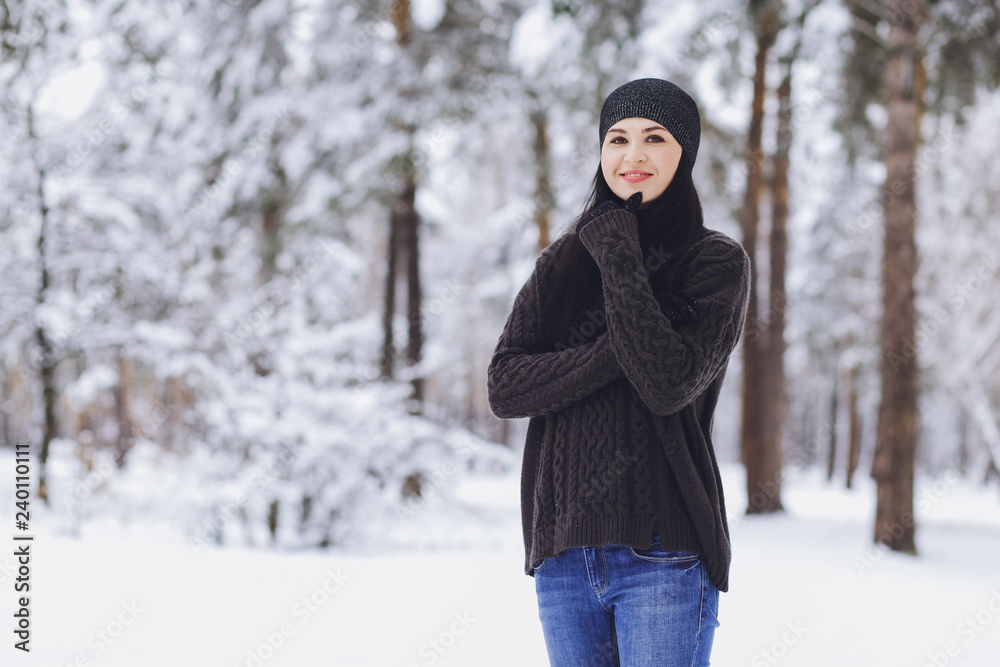 Young beautiful brunette girl in a sweater in the winter snowy forest Young beautiful brunette girl in a sweater in the winter snowy forest