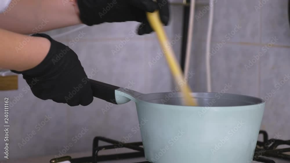 Women's hands are mixed with a wooden spatula food in a ladle on a gas stove. Women's hands are mixed with a wooden spatula food in a ladle on a gas stove.
