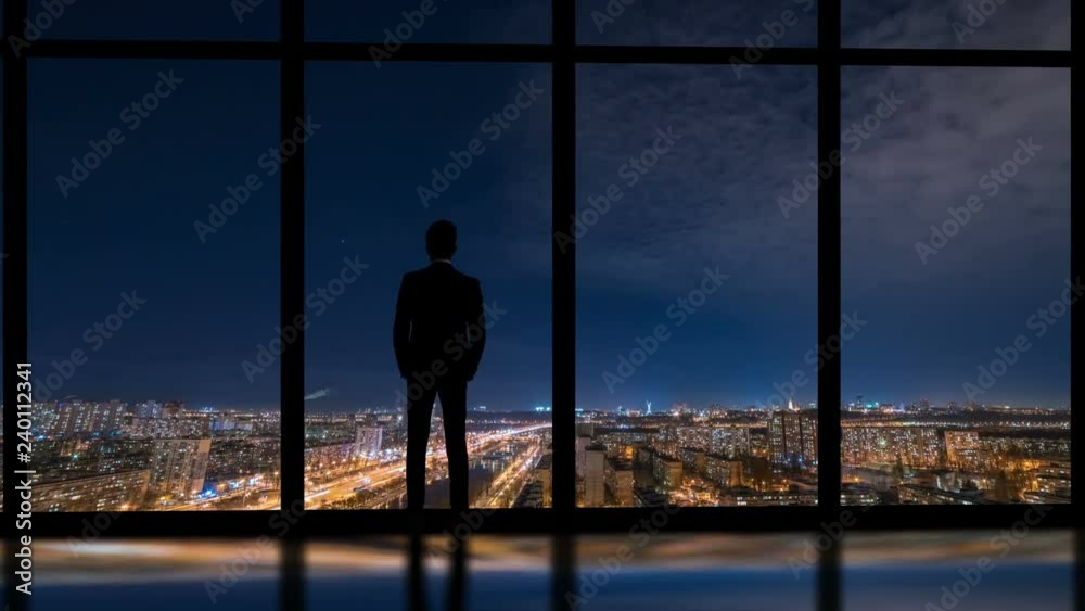 The man standing near window on a night city background. time lapse