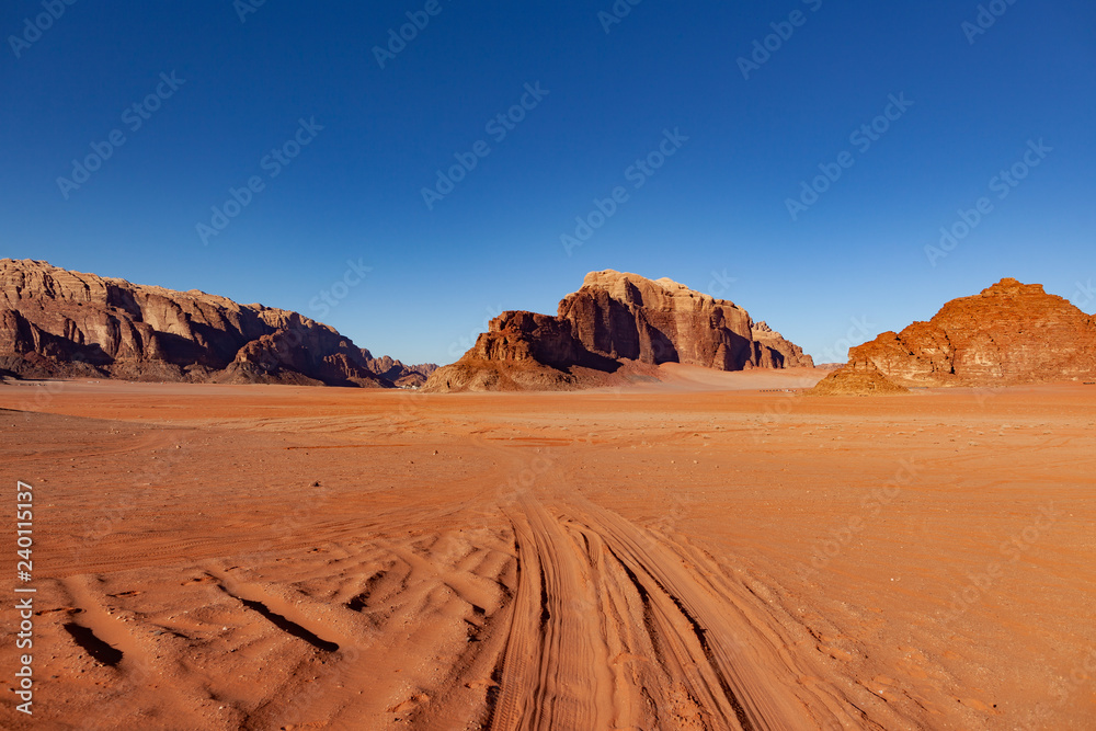 Naklejka premium Red Desert Landscape of Wadi Rum in Jordan, with a sunset, stones, mountains and the sky.