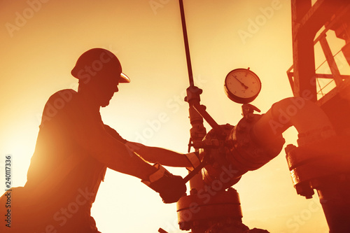 Oil worker is checking the oil pump on the sunset background. photo