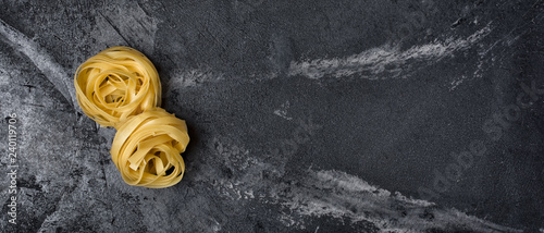 Wide black marble banner with italian raw tagliatelle nests pasta