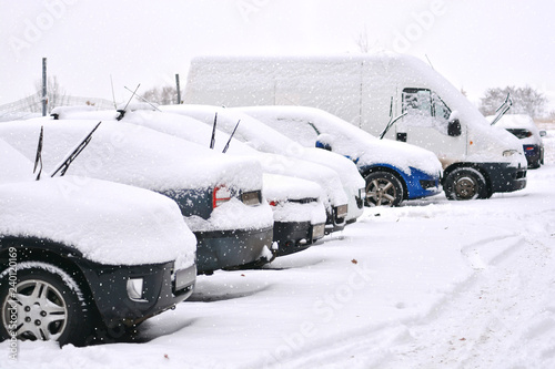 Snow cowered cars on a parking lot. Winter weather.