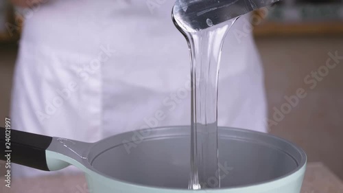 Cook pours the liquid glycerin into the saucepan to reheat. Close-up view.