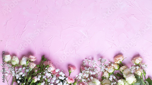 Border from fresh white gypsofila and white rose flowers on  pink textured background. photo