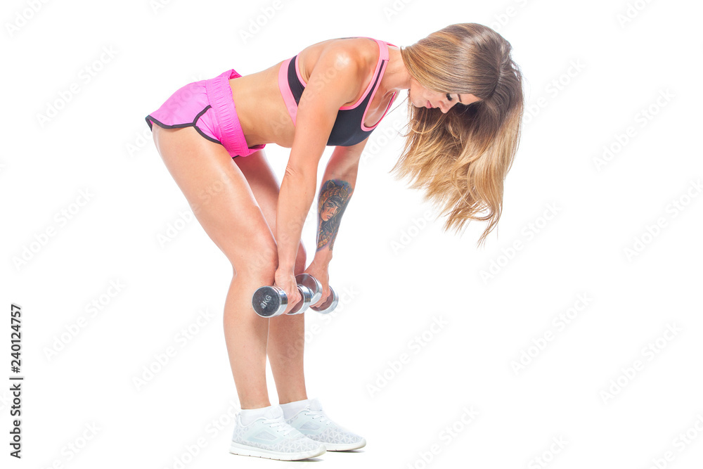 Attractive, sexy, muscular girl in pink shorts and black top makes slopes with dumbbells of steel color. Dead lift. Fitness, healthy lifestyle concept. Isolated on the white background. Attractive, sexy, muscular girl in pink shorts and black top makes slopes with dumbbells of steel color. Dead lift. Fitness, healthy lifestyle concept. Isolated on the white background.