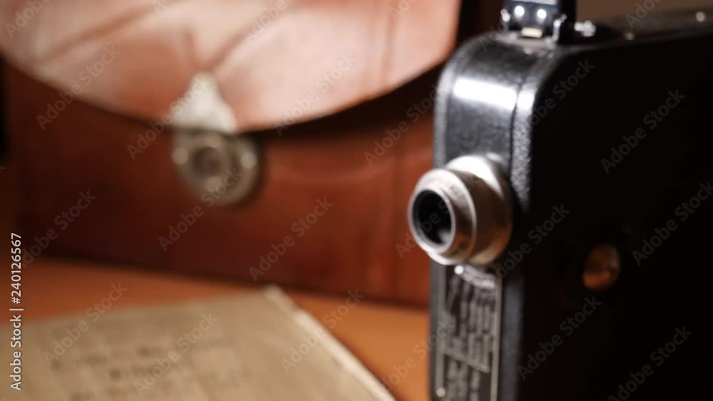 Antique 8mm movie camera with leather bag and printed manual. Slider moves into focus on lens.