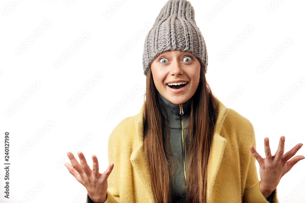 Shoked beautiful bug eyed woman expresses happy emotions and surprise, as if can not believe, that she dressed in warm topcoat and fashionable hat, poses isolated over white background Shoked beautiful bug eyed woman expresses happy emotions and surprise, as if can not believe, that she dressed in warm topcoat and fashionable hat, poses isolated over white background