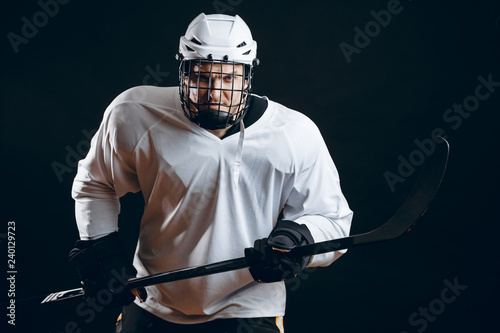 Image of ice-hockey player in white sportswear holding hockey stick prepare to defense.