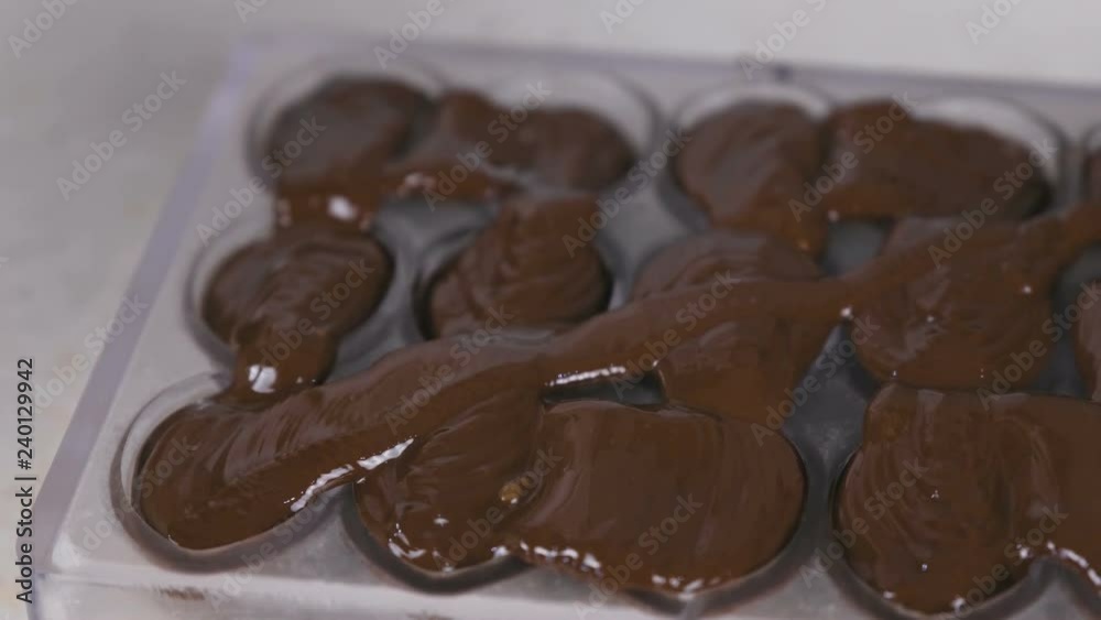 Making homemade praline sweets, pouring chocolate in forms. Close-up view. Making homemade praline sweets, pouring chocolate in forms. Close-up view.
