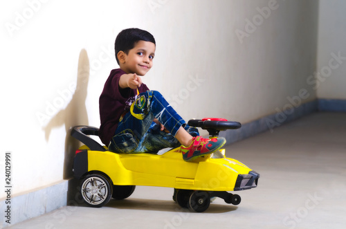asian baby boy rides his toy car