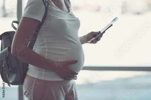 Pregnant woman is traveling by plane standing near the window