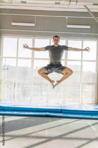active fit man doing yoga while jumping. flying lotus position. flying yoga pose. relaxing in the air. motivation,full length photo