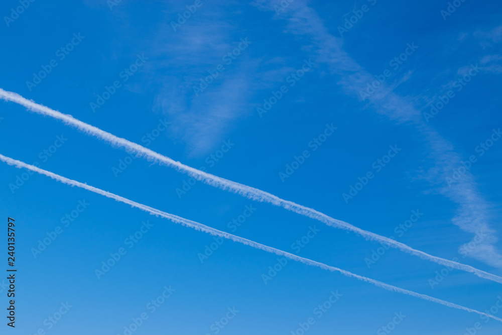 Blue sunny sky with light clouds and traces of flying aircraft Blue sunny sky with light clouds and traces of flying aircraft