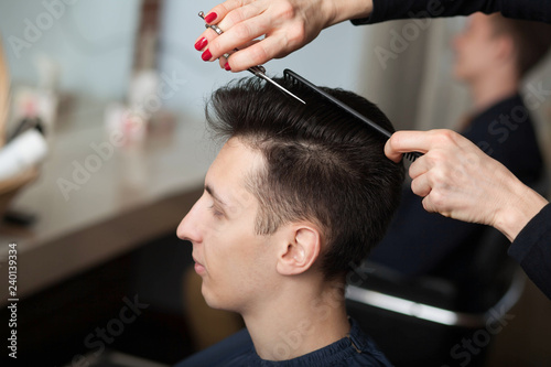 Hairdresser cutting man's hair with scissors. young man having new haircut in barber shop.