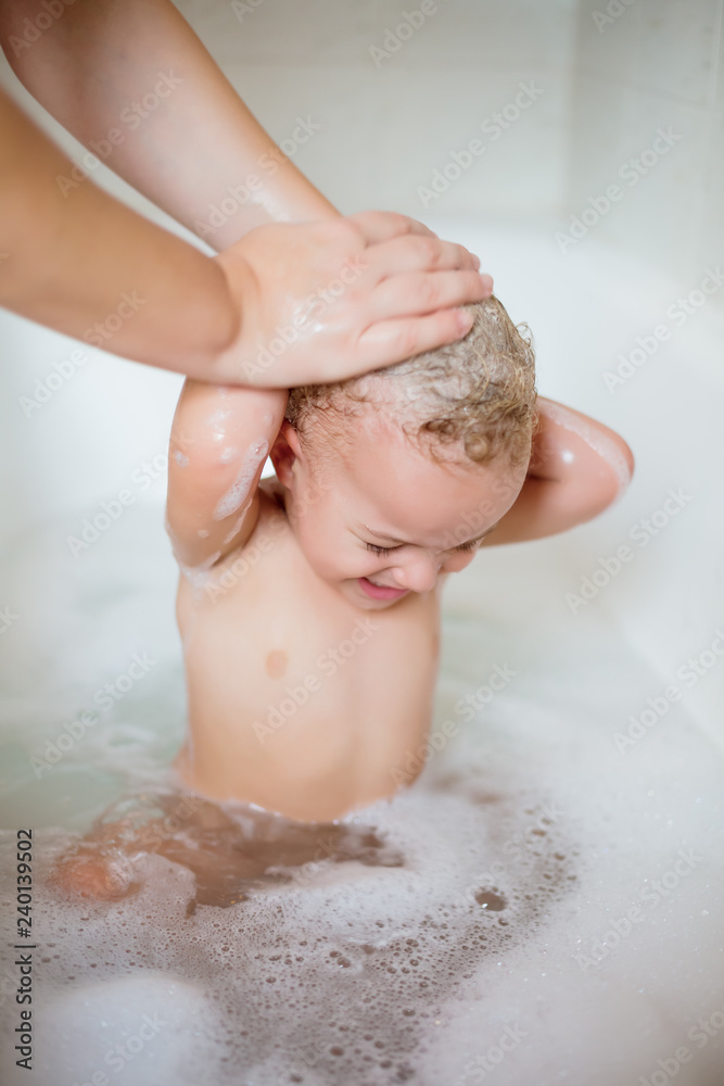 Fototapeta premium Cute two year old boy taking a relaxing bath with foam