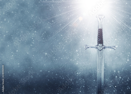 mysterious and magical photo of silver sword over gothic snowy black background. Medieval period concept.