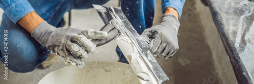 master is applying white putty on a wall and smearing by putty knife in a room of renovating house in daytime BANNER, LONG FORMAT photo