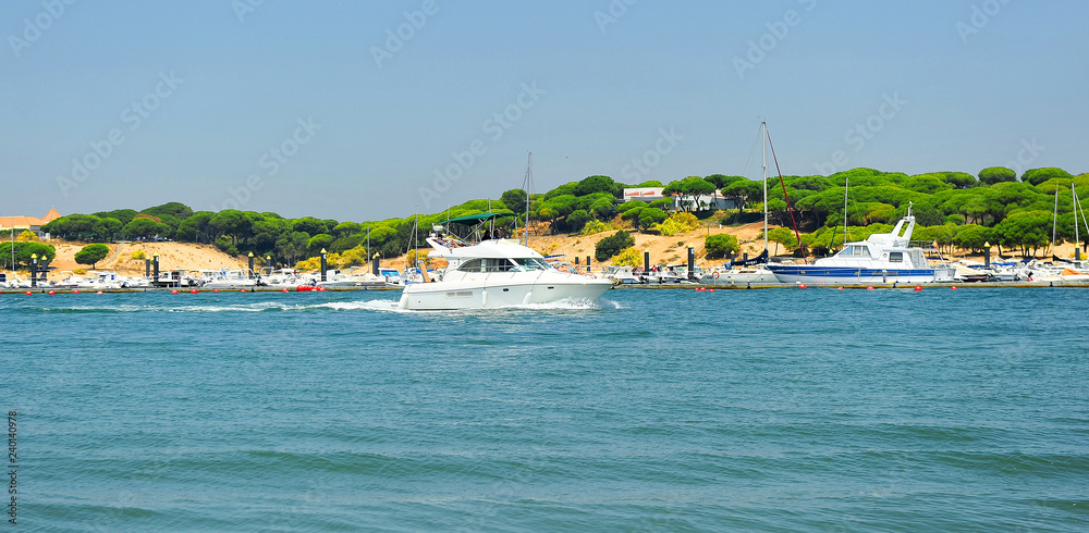 A yacht sails down the River Stones (Rio Piedras) in El Rompido, beaches of Huelva, Andalusia, Spain A yacht sails down the River Stones (Rio Piedras) in El Rompido, beaches of Huelva, Andalusia, Spain