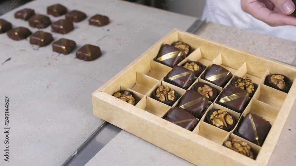 Baker's hands put handmade chocolate candies in a beautiful box. Present box of chocolate sweets.