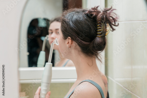 the girl is holding a cosmetic device darsonval for rejuvenation procedures .reflection in the mirror side view