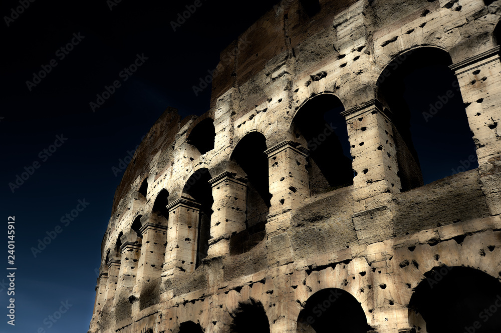 A section of the facade of the Colosseum (Flavian Amphitheatre) in Rome during the blue hour. Night view. Rome, Lazio, Italy