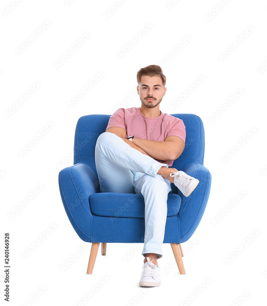 Handsome young man sitting in armchair on white background