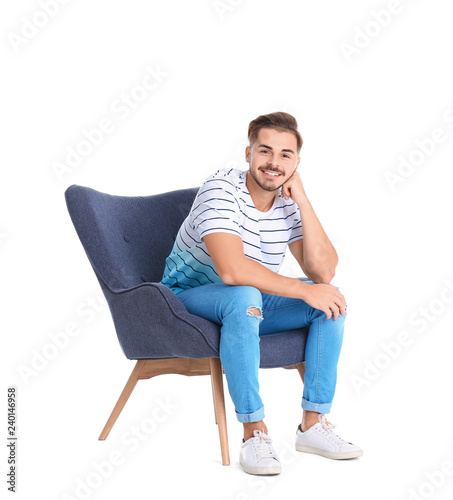 Handsome young man sitting in armchair on white background