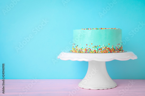 Fresh delicious birthday cake on stand against color background. Space for text