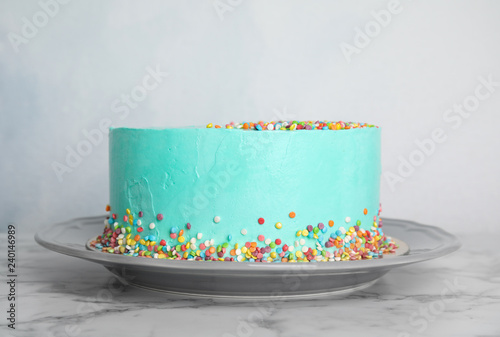 Plate with fresh delicious birthday cake on table against color background