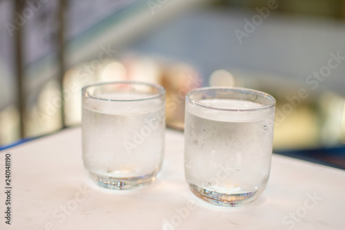 fresh water in glass on white table. soft focus.