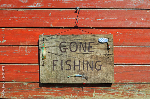 gone fishing sign written on a wooden plaque hanging on a fence