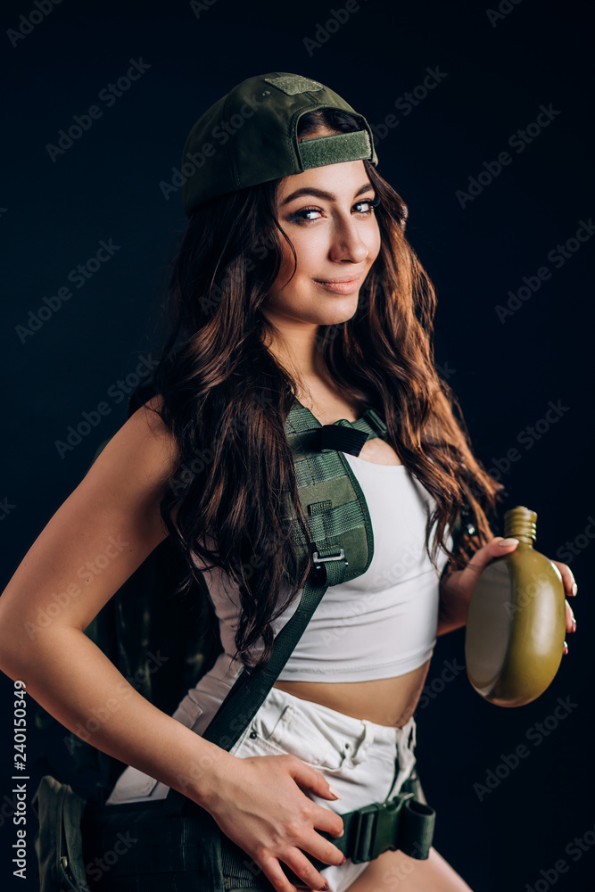 Sexy woman with military riot uniform in studio on dark background. A  beautiful girl in short shorts and a white top holds a flask on her hand  Stock Photo | Adobe Stock