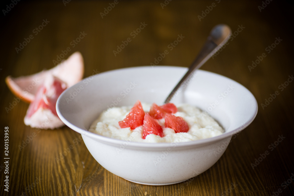 sweet boiled semolina porridge in a plate with slices of red grapefruit