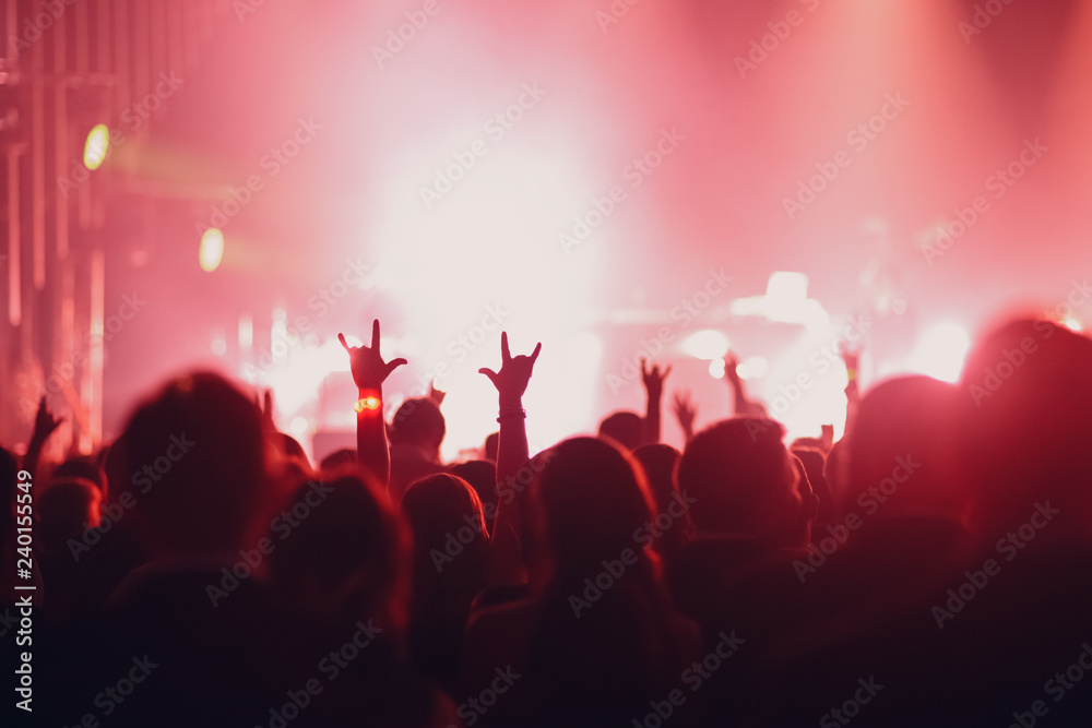 Concert, event or party concept. People with hands up at the scene, spotlight, colored light.