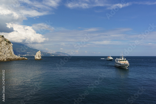 Two white ships sail the calm blue sea on a Sunny day. Cape Limen-Burun and rock Sail in the black sea resort of Crimea