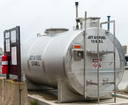 A storage tank for jet fuel. The fuel is JET A1. Fire extinguisher on a sign on the left. Overcast sky.